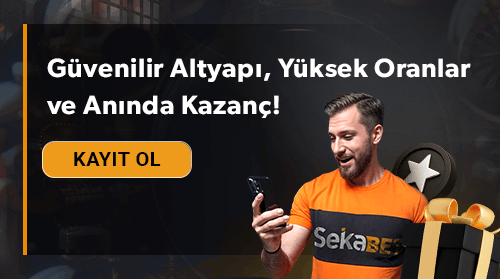 Turuncu forma giyen bir adam telefonuna bakıyor ve yanında hediye kutusu duruyor